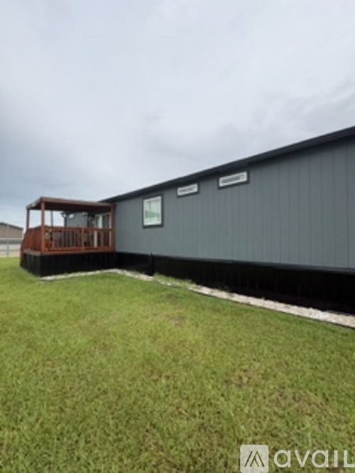 A grey building with a wooden deck in front.