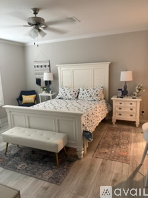 A bedroom with a bed, bench, and two lamps.