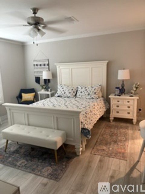 A bedroom with a bed, bench, and two lamps.