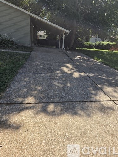 A concrete driveway leads to a garage with a tree in the background.