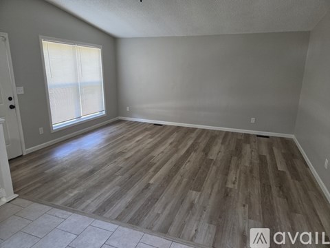 A room with wooden flooring and a window with blinds.