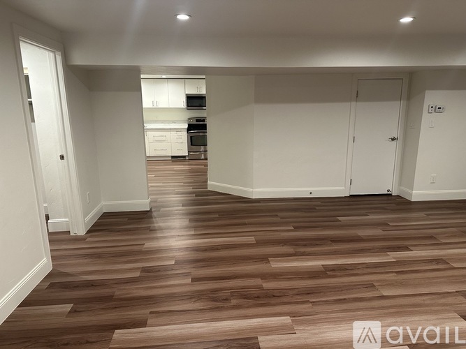 A spacious room with wooden flooring and white walls.