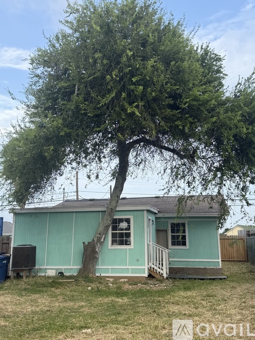 A tree in front of a blue house.