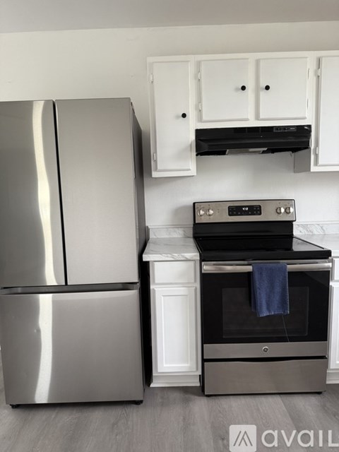 A modern kitchen with a stainless steel refrigerator and an oven with a blue towel on top.
