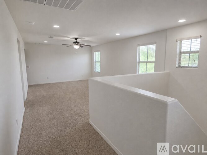 A spacious room with a ceiling fan and carpeted floor.