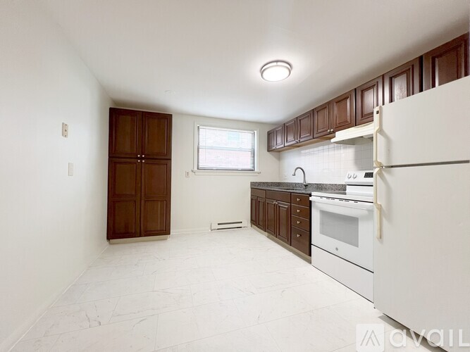 A kitchen with white appliances and brown cabinets.