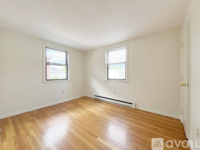A room with wooden floors and two windows.