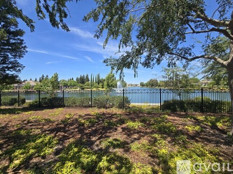 A fenced area with trees and a body of water in the distance.