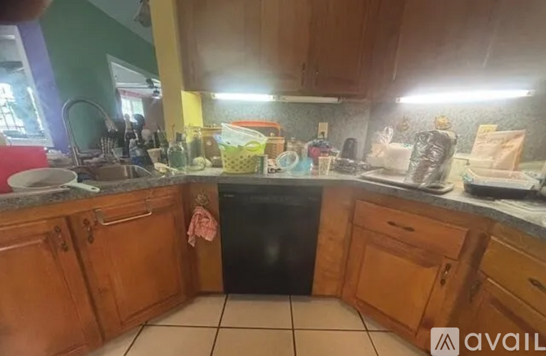 A kitchen with wooden cabinets and a black dishwasher.