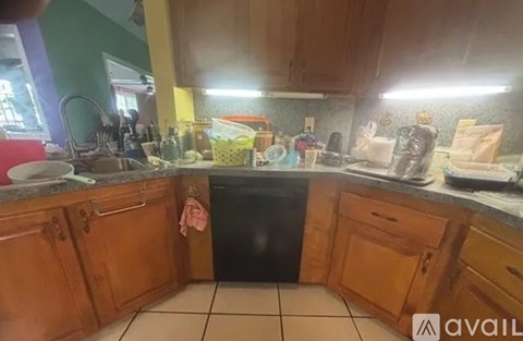 A kitchen with wooden cabinets and a black dishwasher.