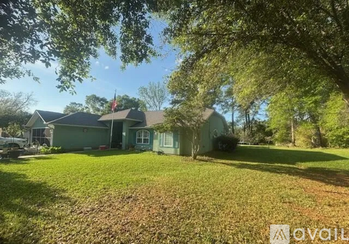 A house with a green lawn and trees in the background.