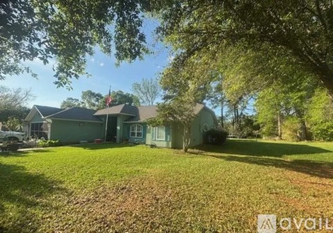 A house with a green lawn and trees in the background.