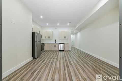 A spacious kitchen with wooden flooring and white walls.