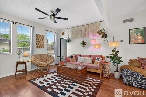 A living room with a brown rug and a brown wicker chair.