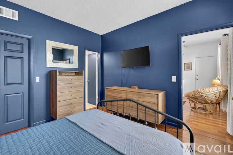 A bedroom with blue walls and a bed in the foreground.