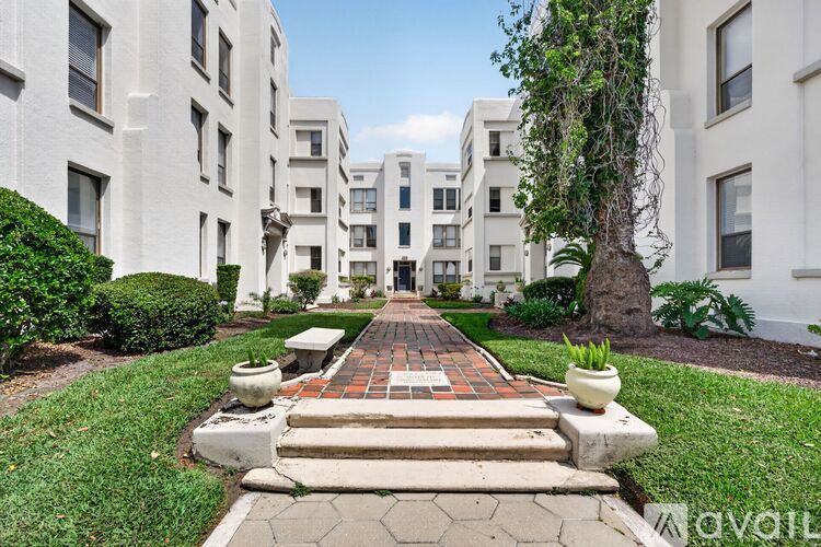 A white building with a tree in front of it.
