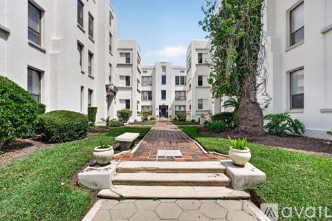 A white building with a tree in front of it.