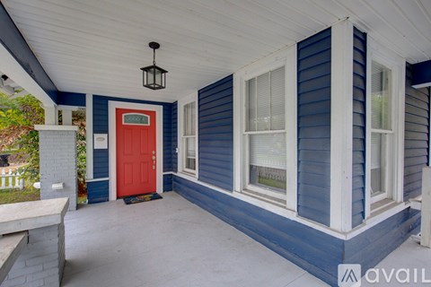 A porch with a red door and a hanging light fixture.