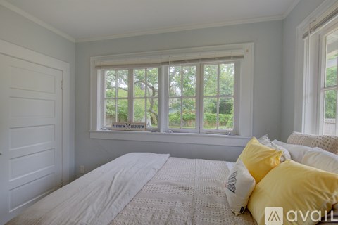 A bedroom with a large bed and a window overlooking a garden.