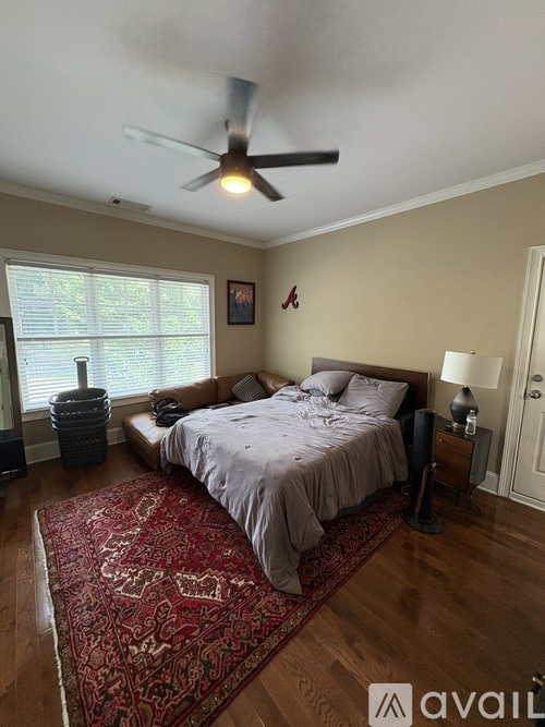 A bedroom with a bed, a ceiling fan, and a rug on the floor.