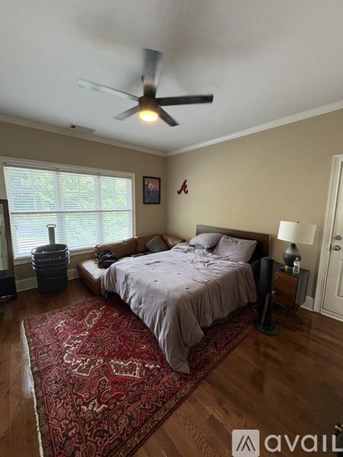 A bedroom with a bed, a ceiling fan, and a rug on the floor.