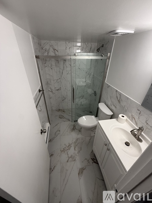A bathroom with marble tiles and a walk-in shower.