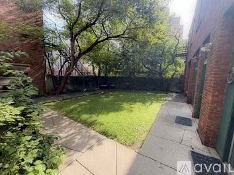 A backyard with a tree and a brick building.