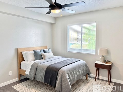 A bedroom with a bed, nightstand, and window.