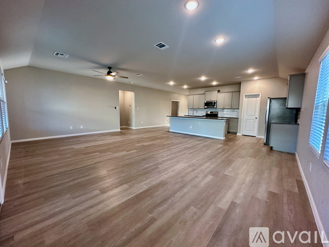 A spacious room with wooden flooring and a ceiling fan.