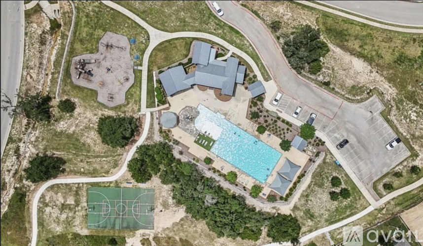 An aerial view of a resort with a basketball court, swimming pool, and tennis court.