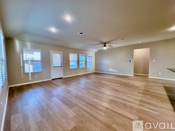 A spacious room with wooden flooring and a ceiling fan.