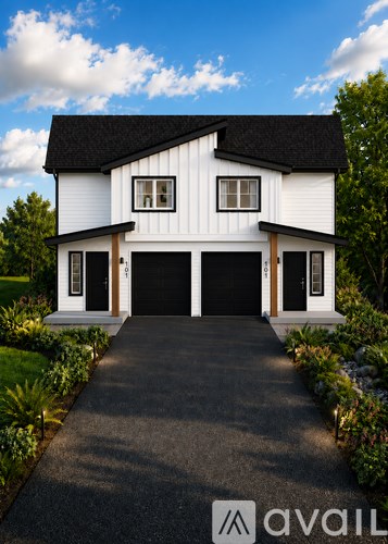 A white house with a black roof and a driveway leading to the garage.