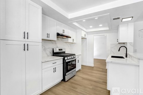 A modern kitchen with white cabinets and a wooden floor.