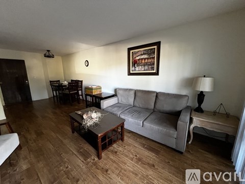 A living room with a grey couch, wooden coffee table, and a painting on the wall.