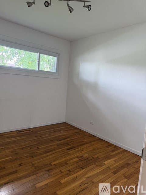 A room with wooden flooring and a window letting in natural light.