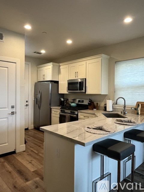 A kitchen with white cabinets and a marble countertop.