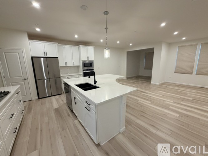A modern kitchen with wooden floors and white cabinetry.