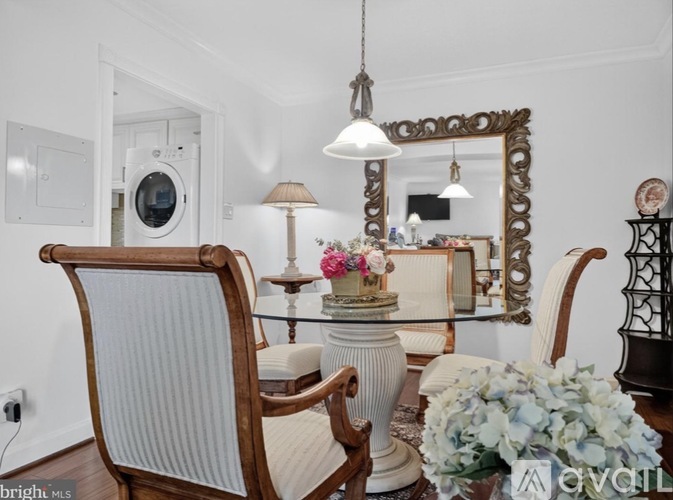 A dining room with a wooden chair and a table with a vase of flowers on it.