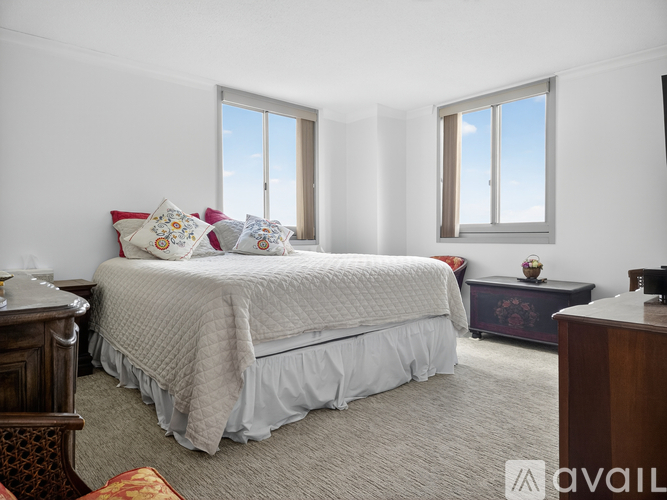 A bedroom with a large bed and two windows.