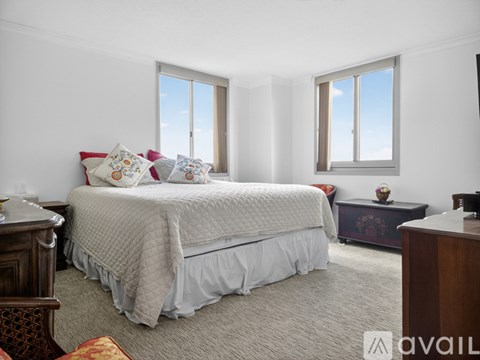 A bedroom with a large bed and two windows.
