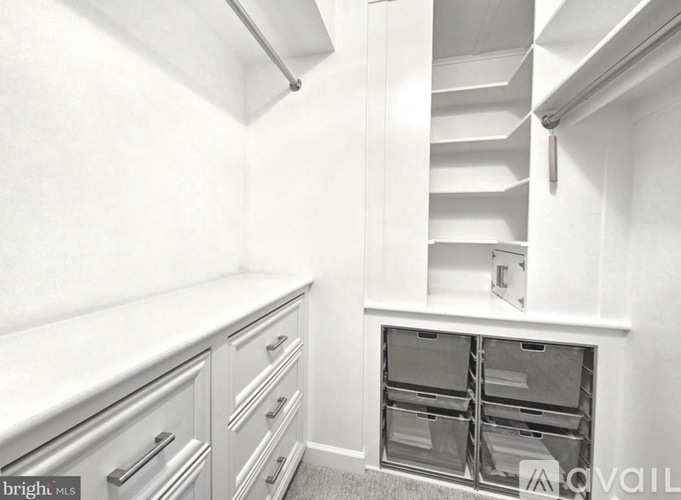 A kitchen with white cabinets and drawers, a stainless steel handle, and a white countertop.