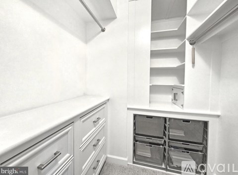 A kitchen with white cabinets and drawers, a stainless steel handle, and a white countertop.