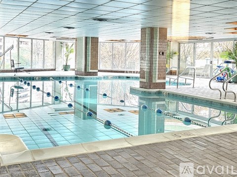 A large indoor swimming pool with a glass wall and tiled floor.