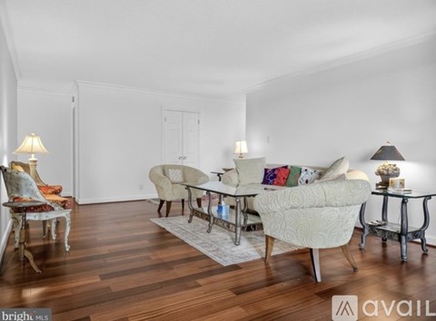 A living room with a white couch and a wooden floor.
