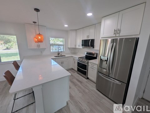 A modern kitchen with white cabinets and stainless steel appliances.