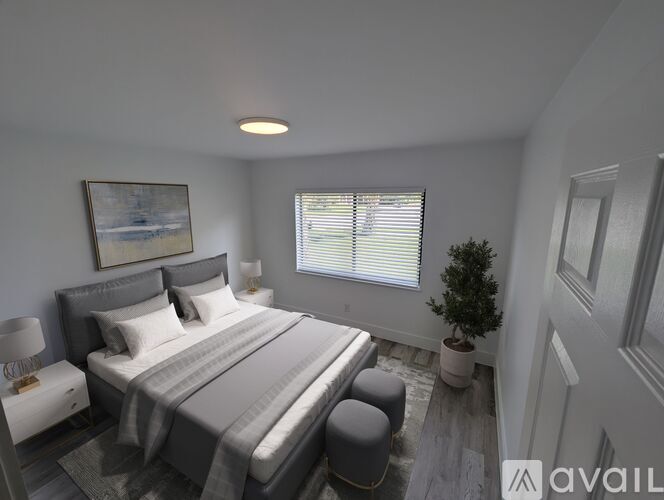 A bedroom with a large bed and a small potted plant by the window.
