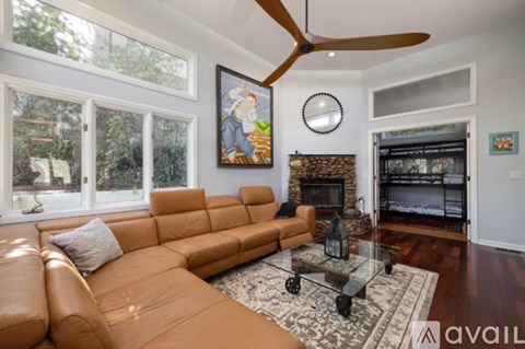 A living room with a brown leather couch and a fireplace.