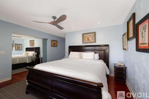 A bedroom with a large bed and a ceiling fan.