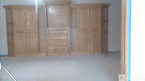 A room with a large wooden wardrobe and drawers.