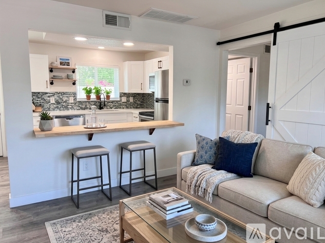 A kitchen with white cabinets and a bar area with two stools.